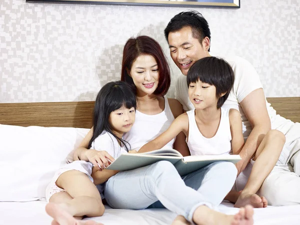 Asiática família com duas crianças ler livro no quarto — Fotografia de Stock