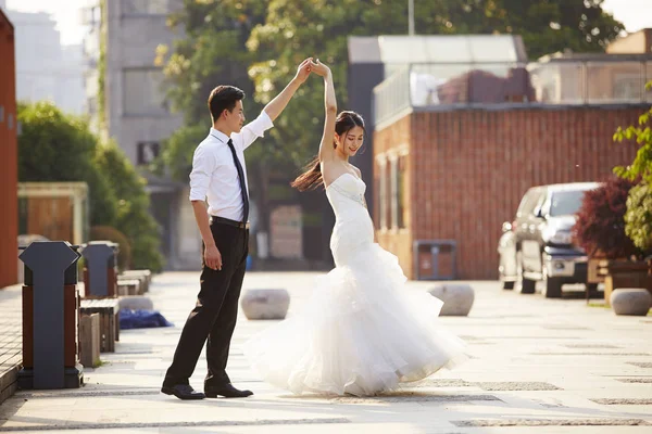 Asian bride and groom dancing in parking lot — Stock Photo, Image