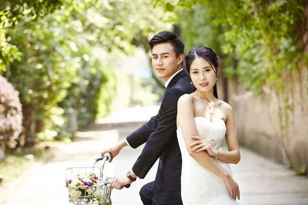 Asian wedding couple riding bicycle — Stock Photo, Image