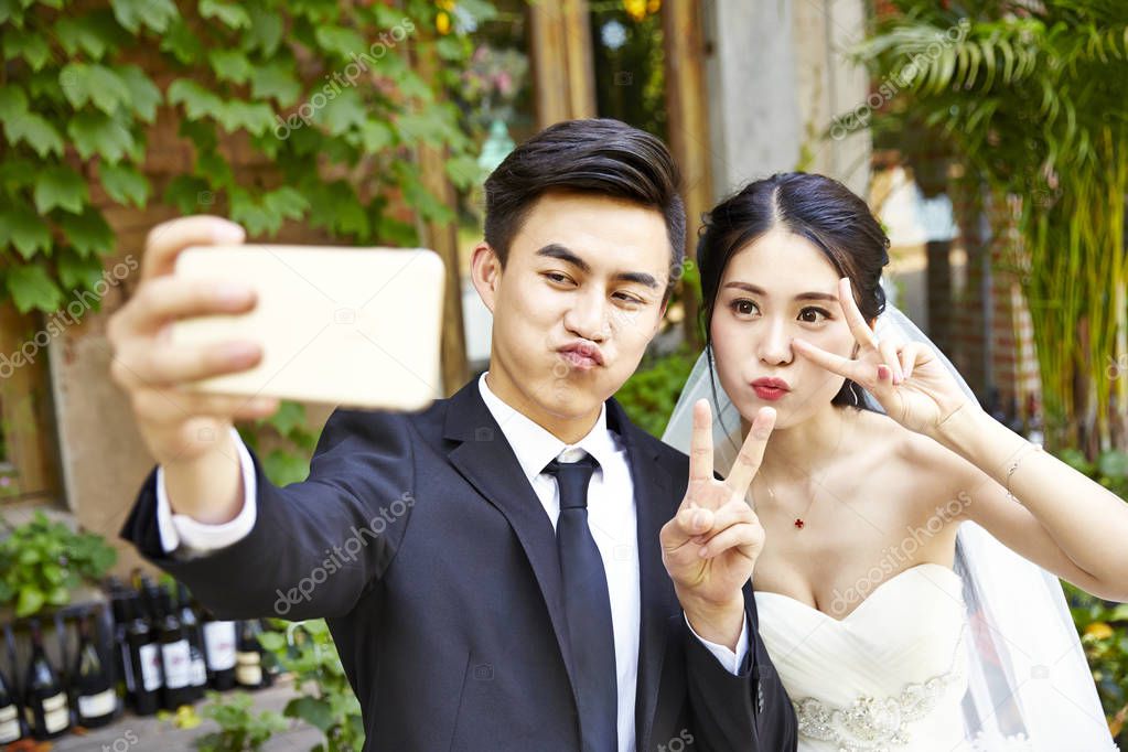 young asian bride and groom taking a selfie