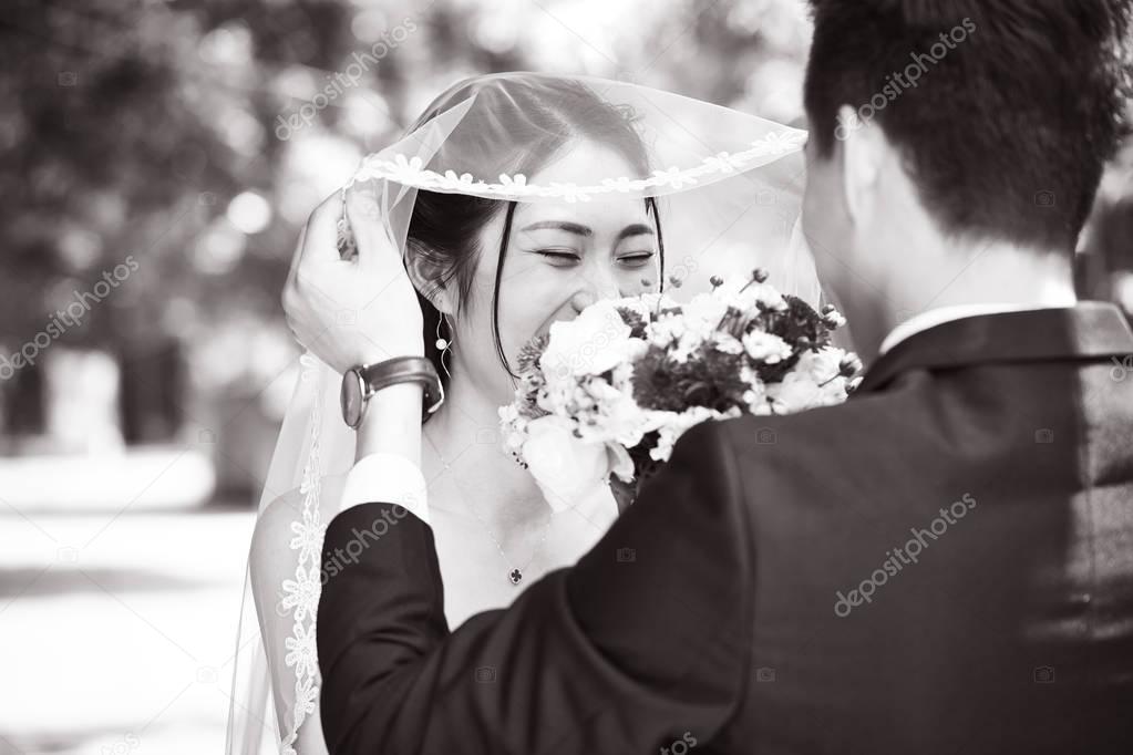 asian groom lifting up bridal veil