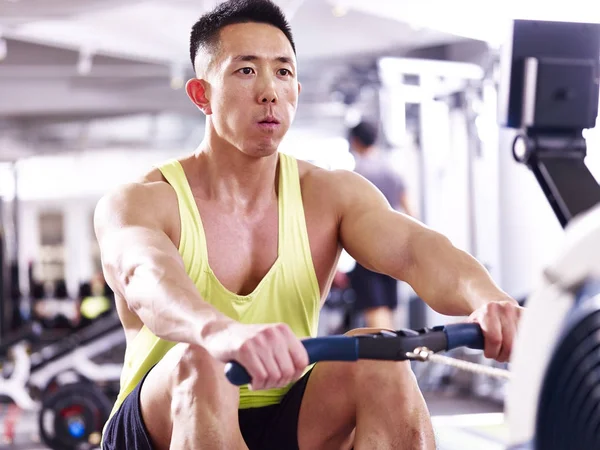 Young asian man working out using rowing machine — Stock Photo, Image
