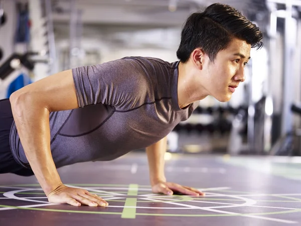 Young asian man doing push-ups in gym — Stock Photo, Image