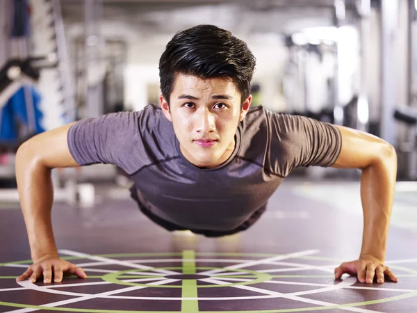 Fiatal ázsiai ember csinál fekvőtámaszokat a tornaterem — Stock Fotó