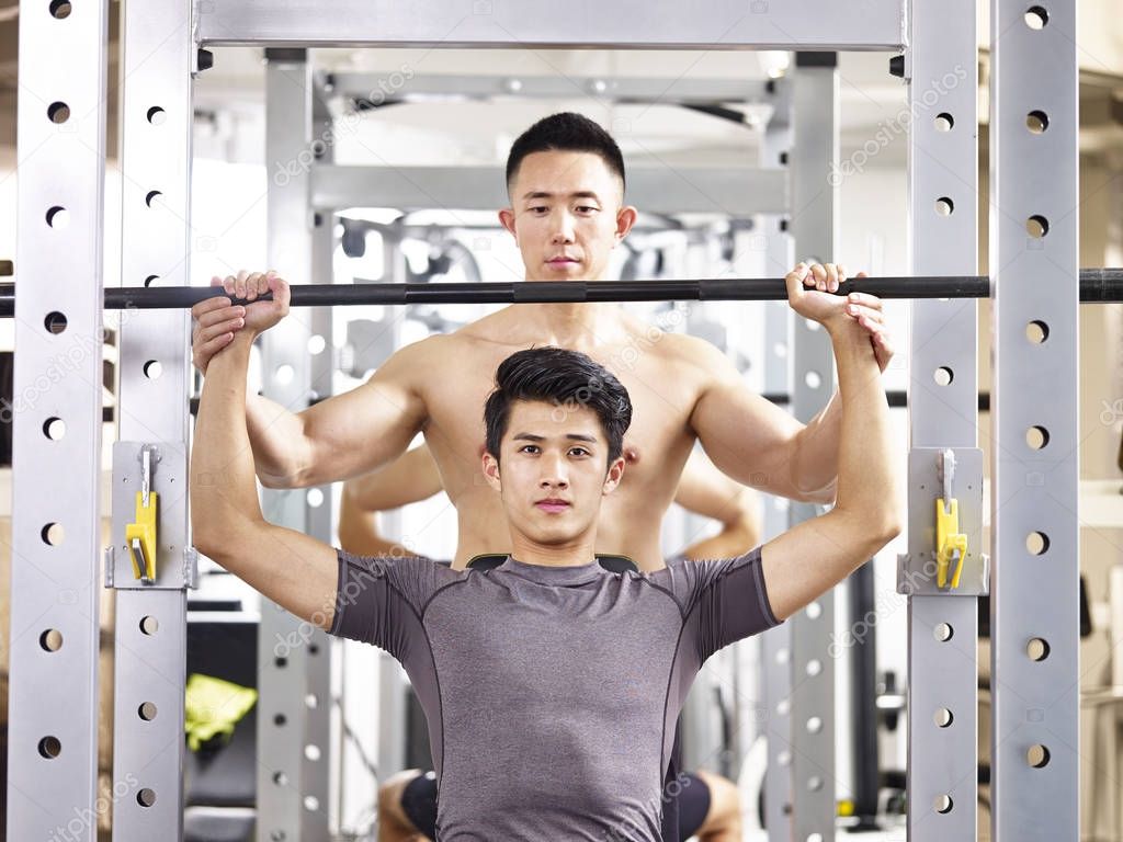 young asian man lifting weight in gym