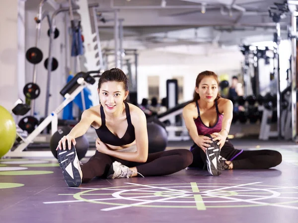 Jonge Aziatische vrouwen, die zich uitstrekt benen in de sportschool — Stockfoto