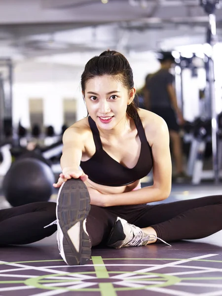 Joven asiático mujer estiramiento piernas en gimnasio — Foto de Stock