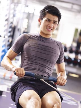 Asya genç adam kürek makine üzerinde çalışma dışarı