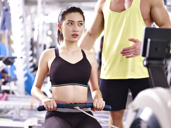 Young asian adult woman exercising using rowing machine — Stock Photo, Image