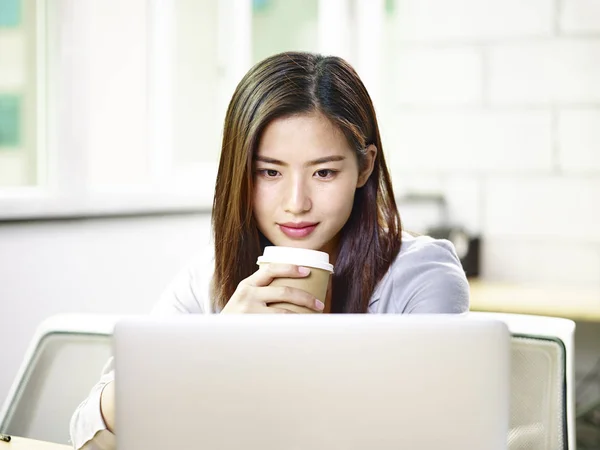 Unga asiatiska affärskvinna tittar på laptop i office — Stockfoto