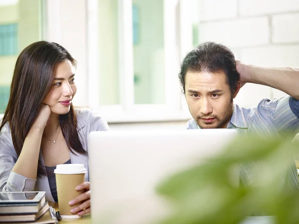 Giovani compagni di squadra asiatici che lavorano insieme in ufficio utilizzando laptop co — Foto Stock