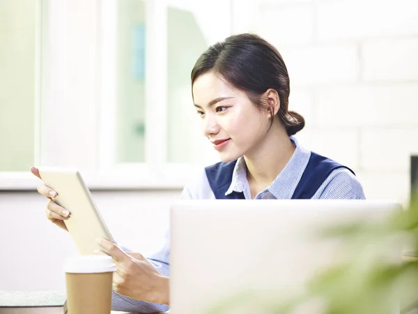 Молода азіатська бізнес-леді працює в офісі за допомогою ноутбука і копати — стокове фото