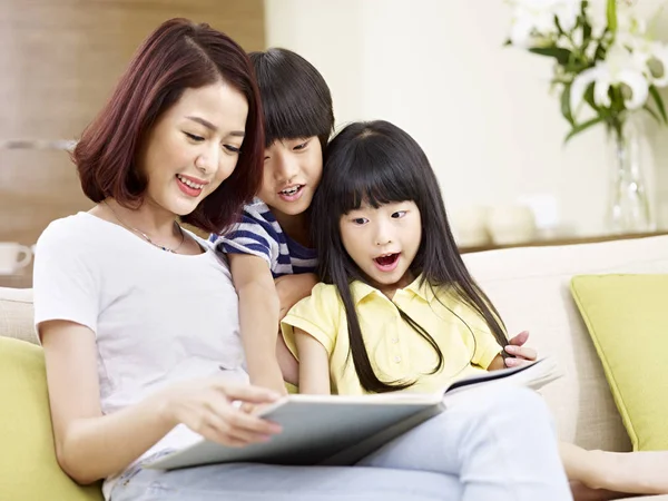 Asian mother reading story to two children — Stock Photo, Image