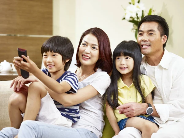 Ασιατική οικογένεια με δύο παιδιά βλέποντας τηλεόραση στο σπίτι — Φωτογραφία Αρχείου