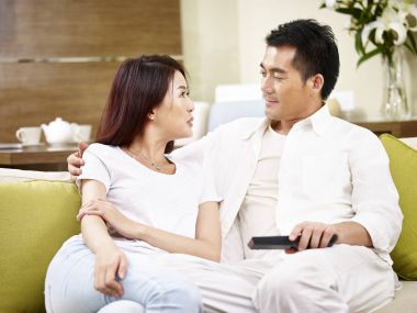 Asya çift oturan ve evde kanepede konuşuyor