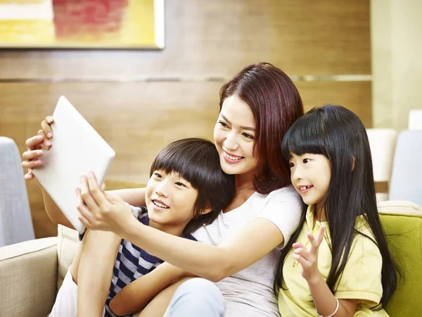 Азіатська мати і двоє дітей беруть селфі за допомогою цифрового табло — стокове фото