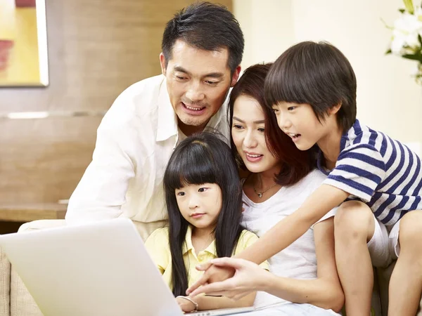 Familia asiática con dos niños usando ordenador portátil juntos —  Fotos de Stock