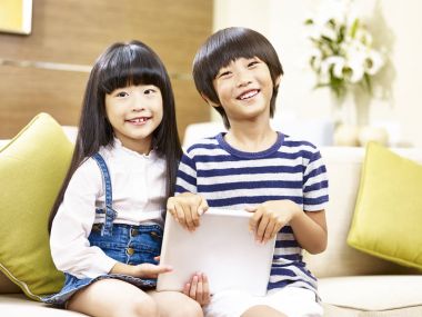 kamera gülümseyen arıyor kanepede oturan iki Asyalı çocuk