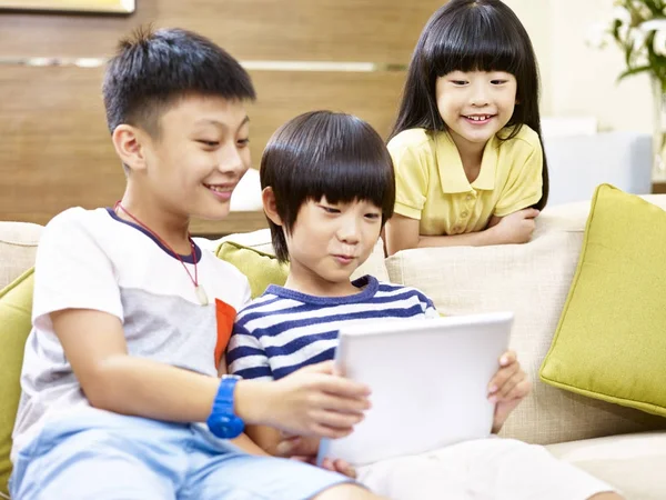 Drie Aziatische kinderen spelen met digitale tablet — Stockfoto