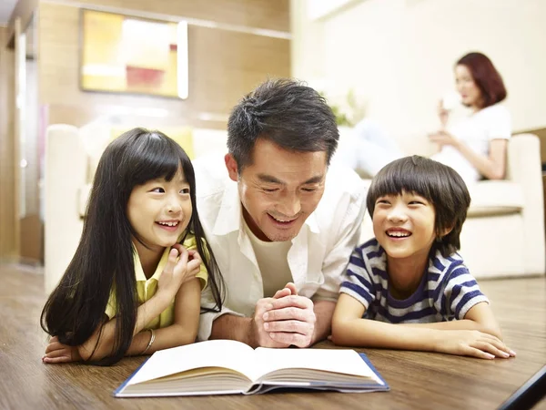 Asian father reading book telling story to two children — Stock Photo, Image