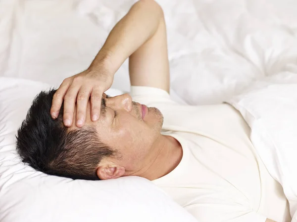 Asiatischer Mann liegt auf dem Rücken im Bett — Stockfoto