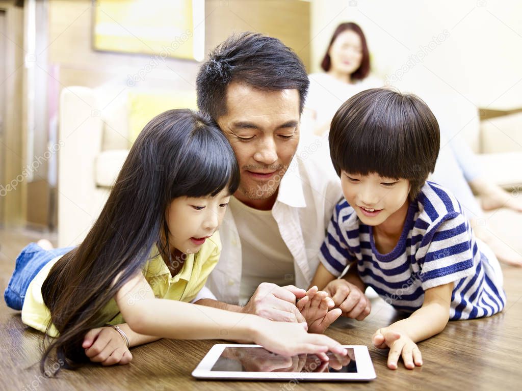 asian father and two children using digital tablet together