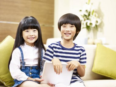 kamera gülümseyen arıyor kanepede oturan iki Asyalı çocuk