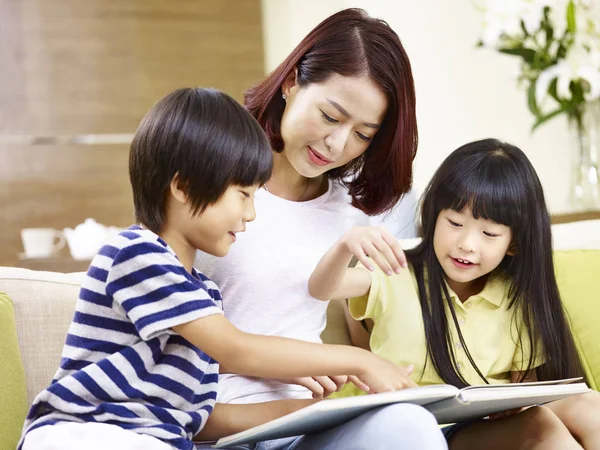 Asiatica madre e due bambini leggendo un libro a casa — Foto Stock