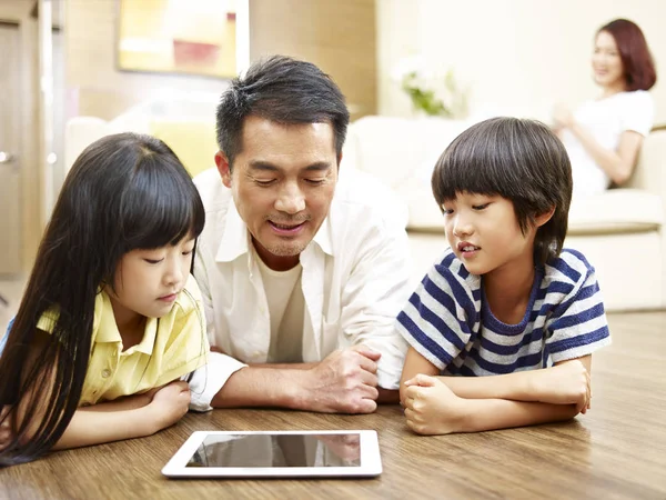 Asya baba ve iki çocuk dijital tablet birlikte kullanma — Stok fotoğraf