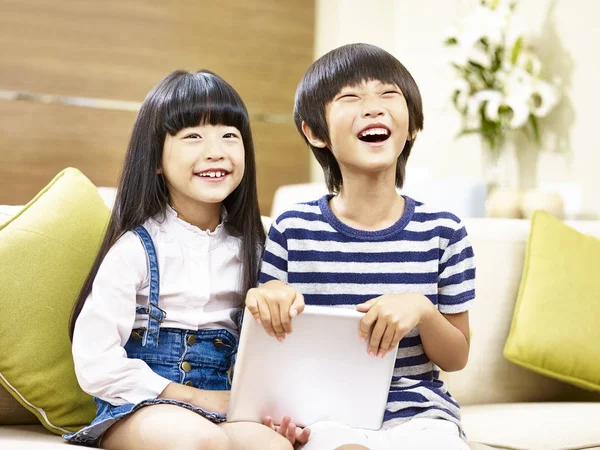 Dos asiático niños sentado en sofá riendo — Foto de Stock