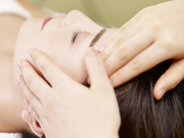 Mladá asijská žena přijímá masáž obličeje ve spa salonu — Stock fotografie