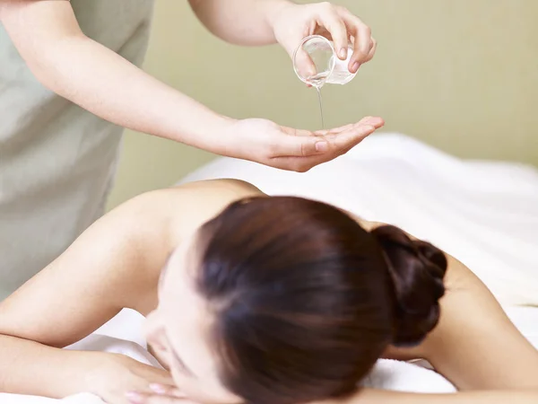 Massagista realizando massagem de óleo em jovem mulher asiática — Fotografia de Stock