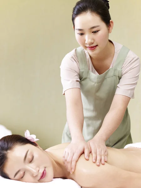 Молодой азиатский массажист, выполняющий массаж женщины — стоковое фото
