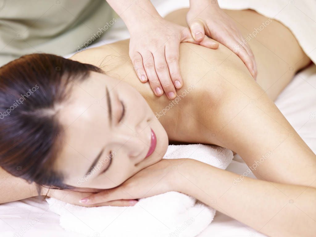 beautiful young asian woman receiving massage in spa salon