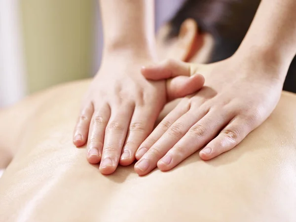 Hands of masseur performing massage on young asian woman — Stock Photo, Image