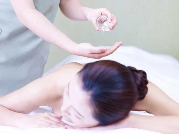 Massagista realizando massagem de óleo em jovem mulher asiática — Fotografia de Stock