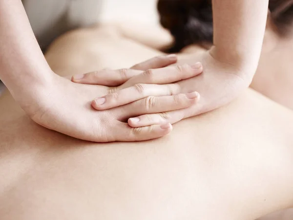 Mãos de massagista realizando massagem no jovem mulher asiática — Fotografia de Stock