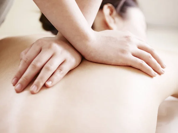 Handen van de masseuse massage uitvoeren op jonge Aziatische vrouw — Stockfoto