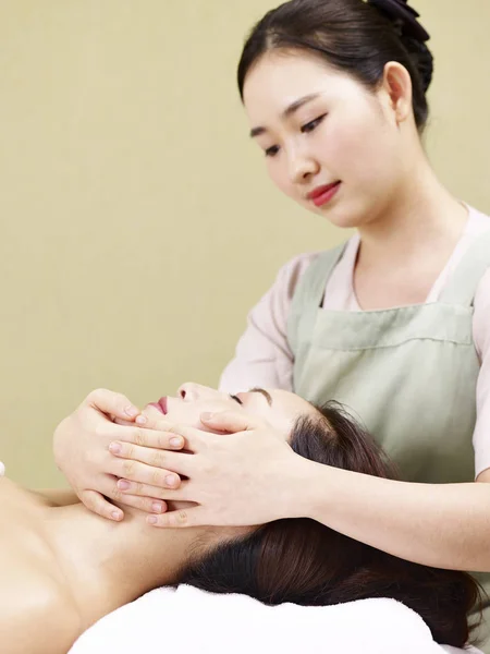 Junge asiatische Masseur Durchführung Gesicht Massage auf Frau — Stockfoto