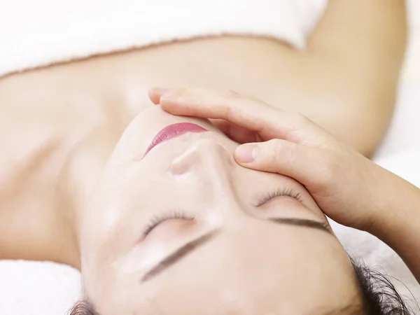 Giovane donna asiatica riceve massaggio facciale nel salone spa — Foto Stock