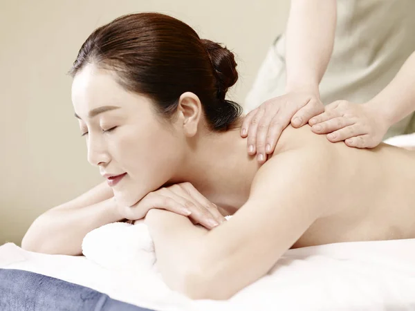 young asian woman receiving massage in spa salon