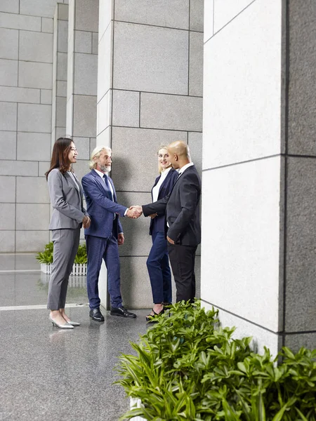 Багатонаціональні корпоративні керівники тремтять руками у вестибюлі режиму — стокове фото