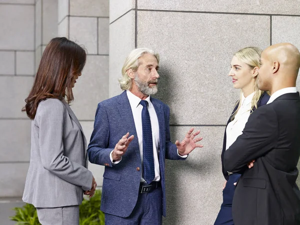 Ejecutivos corporativos multiétnicos de pie hablando en el vestíbulo de m —  Fotos de Stock