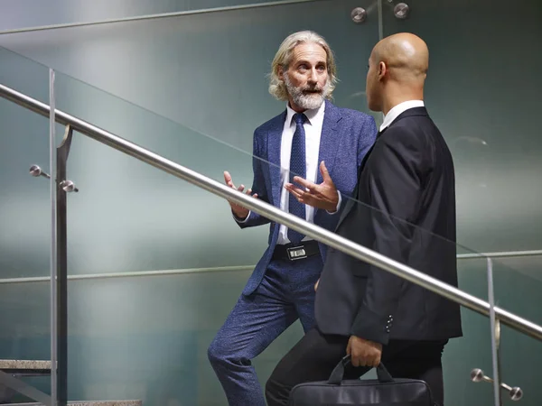 Dos ejecutivos corporativos hablando mientras suben escaleras — Foto de Stock