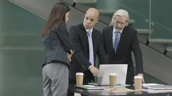 Tres ejecutivos corporativos reunidos en una oficina moderna — Foto de Stock