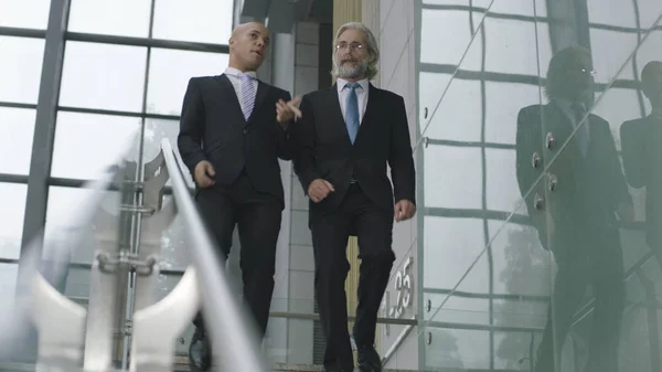 Dos ejecutivos corporativos hablando mientras bajan escaleras — Foto de Stock