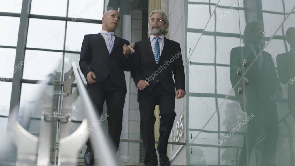 two corporate executives talking while descending stairs