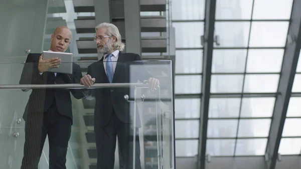 Dos ejecutivos corporativos de pie y hablando en la oficina moderna b — Foto de Stock