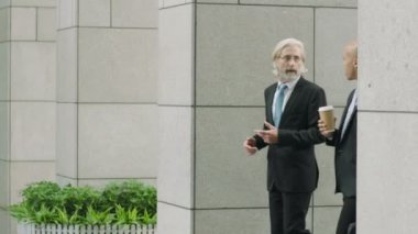 kahve ve modern binaya girerken konuşmak yürüme çanta tutan iki iş adamı.
