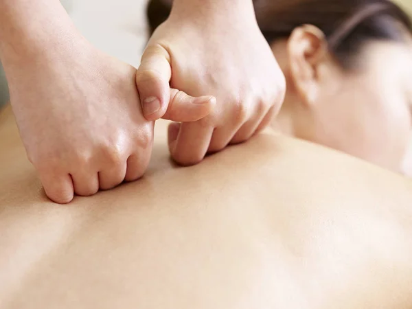 Руки массажиста, выполняющего массаж молодой азиатской женщины — стоковое фото